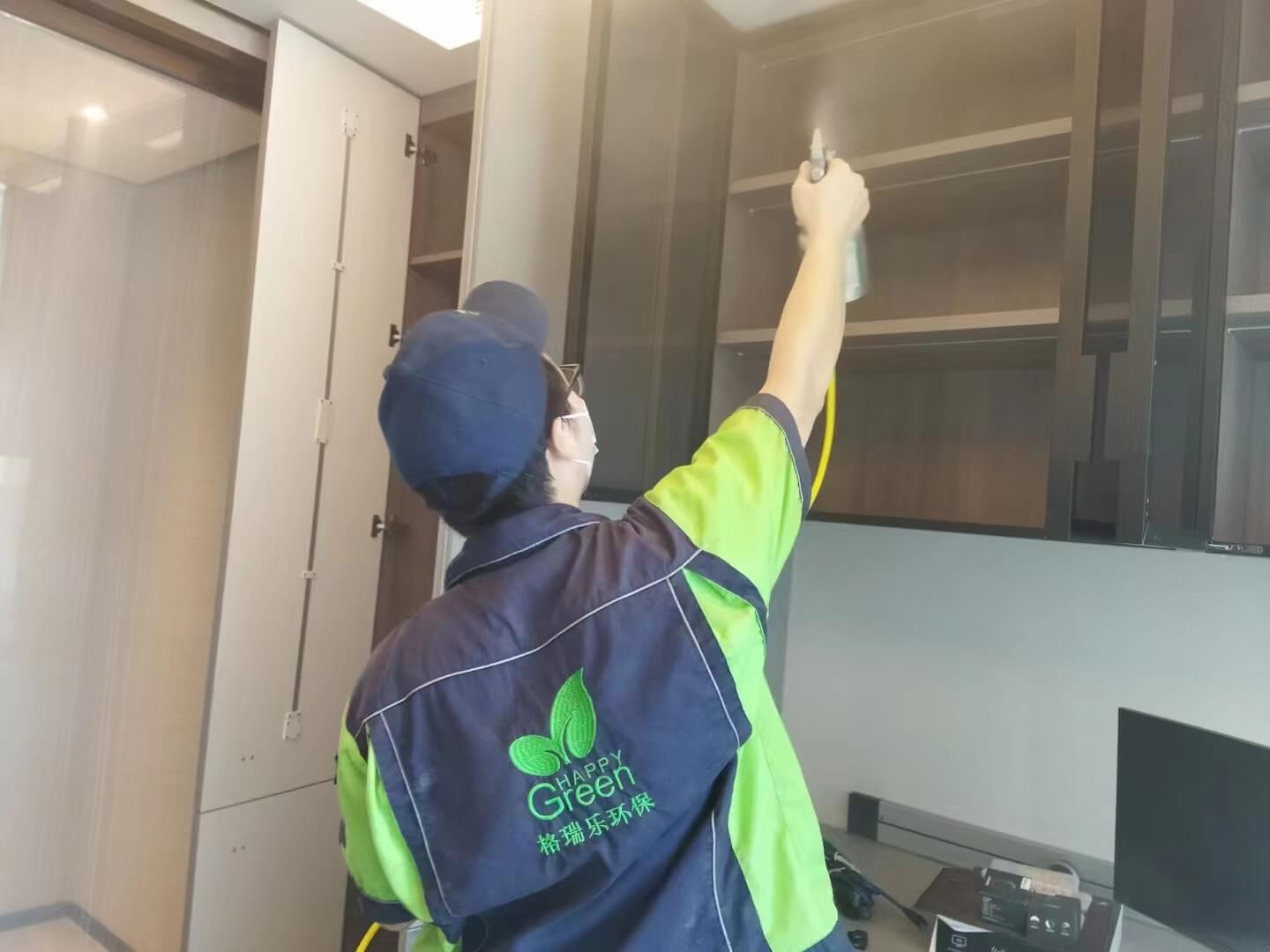 工人在新房书房，对电脑桌下方的插座区域进行除甲醛安全检查与处理。