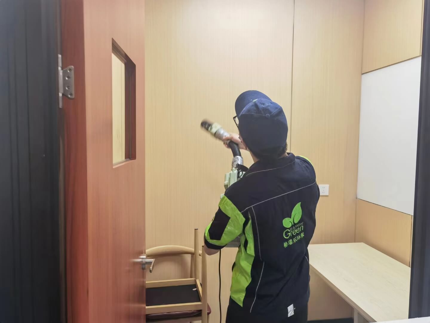新房客厅，工作人员在电视背景墙的插座面板上粘贴格瑞乐除甲醛的防护贴纸。